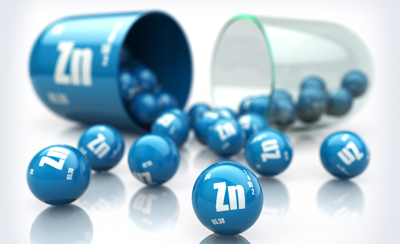 An illustration of a blue zinc capsule with many smaller round blue balls labeled "Zn" spilling out.